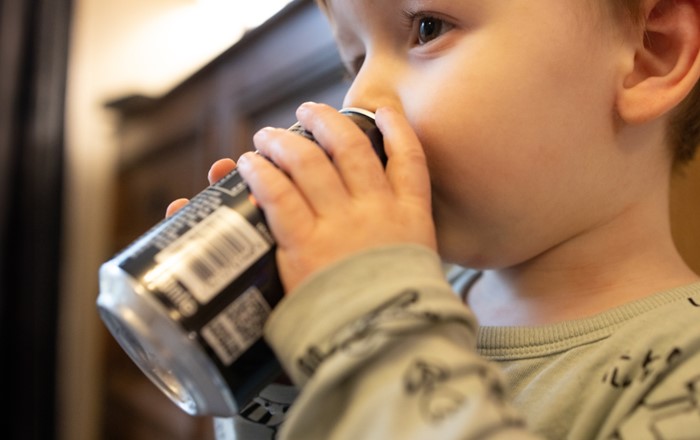 A young child drinking a fizzy, sugar-sweetened drink.