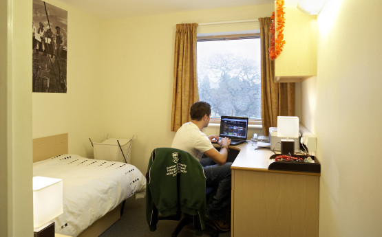 a university bedroom with a student at a desk