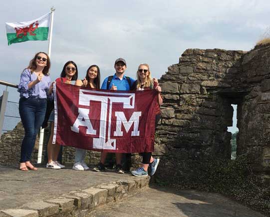 ATM University students in Ostyermouth Castle, Welsh Flag in background.