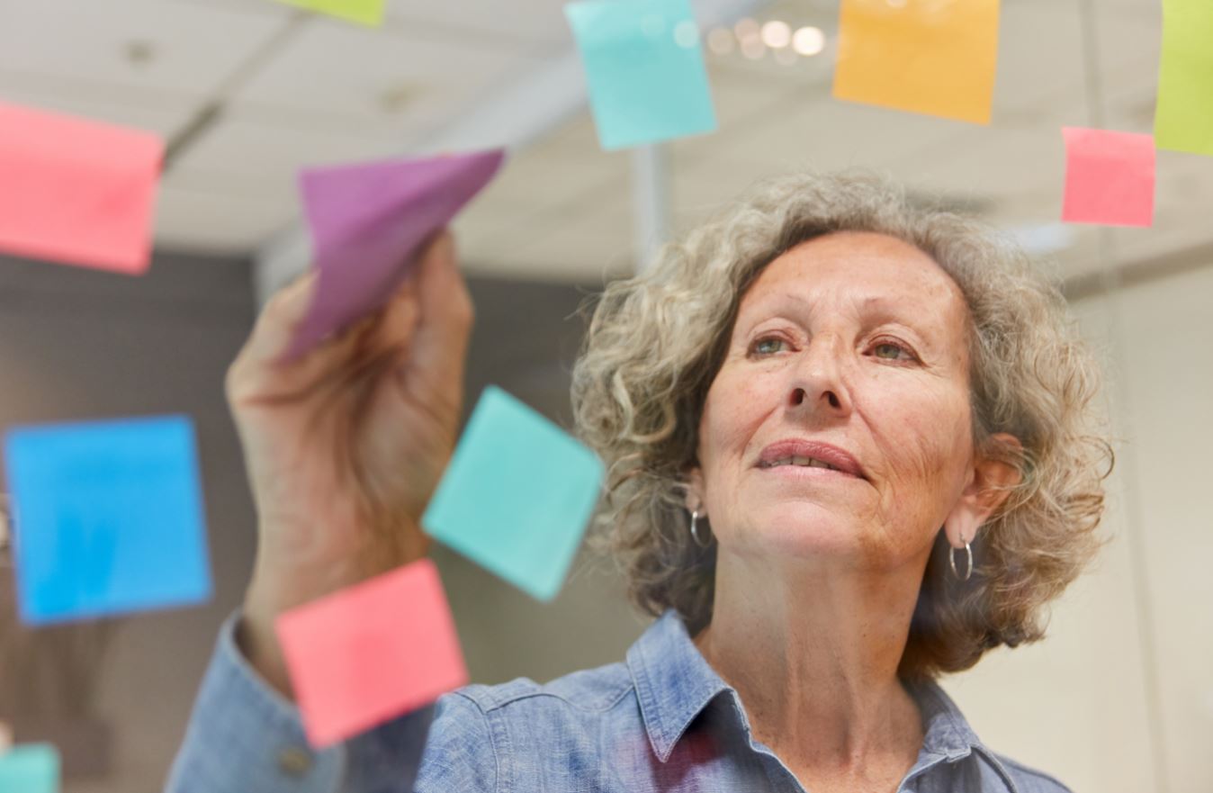 Picture of middle aged woman with small coloured pieces of paper floating in the air around her.