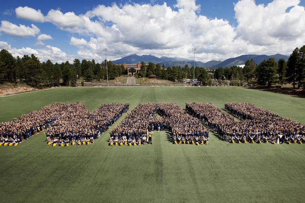 Students stood on a field in the shape of the letters NAU