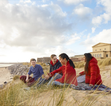 Students sitting in the dunes at Bay Campus
